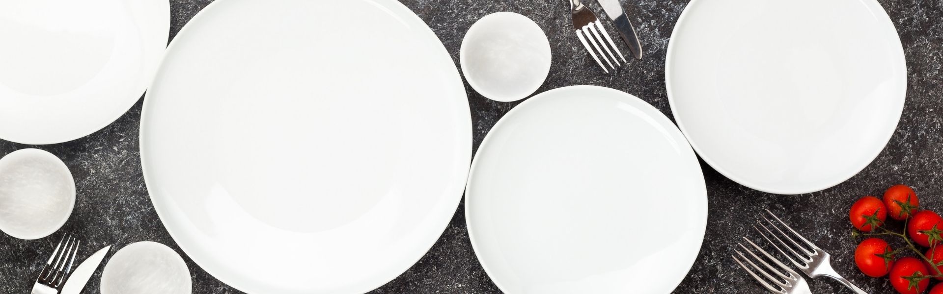 Gedeckter Tisch Teller und Besteck auf dunklem Hintergrund