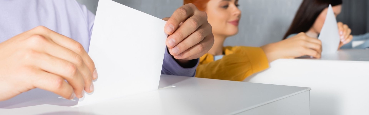 Wähler beim Einwerfen der Stimmzettel in die Wahlurnen vor unscharfem Hintergrund