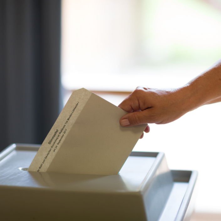 Stimmzettel wird in Wahlurne geworfen